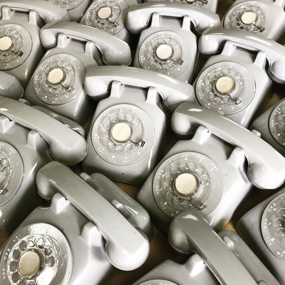 A collection of the same grey rotary dial telephones.