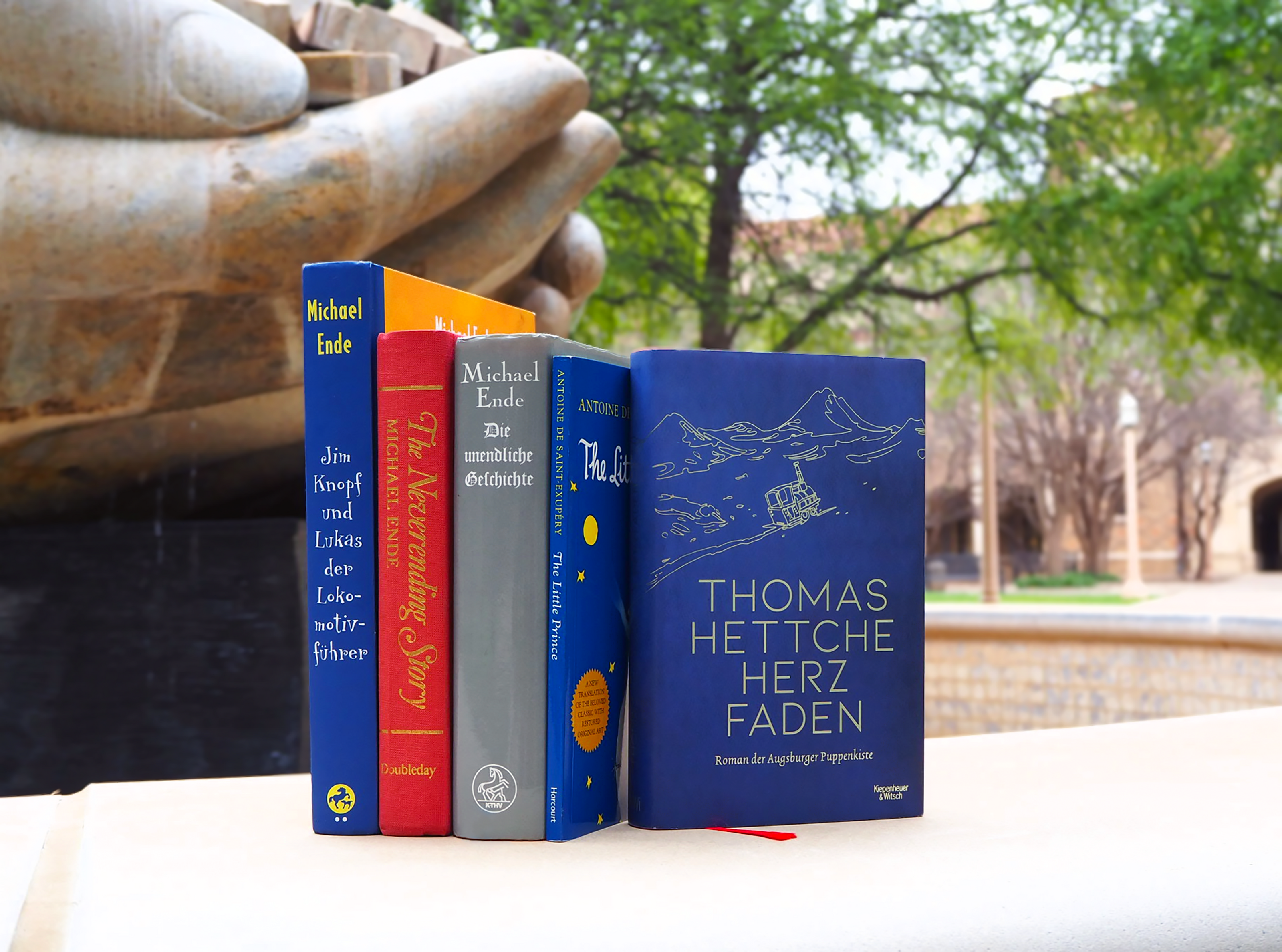 Grouping of books Marni studied positioned in front of a fountain at the TTU campus.